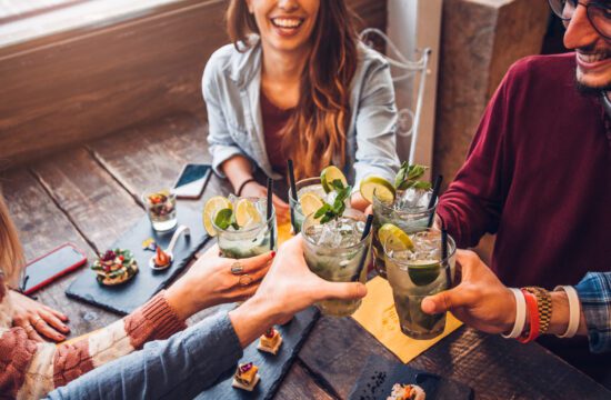 friends drinking mojitos at a bar, enjoying drinks and food at a trendy restaurant