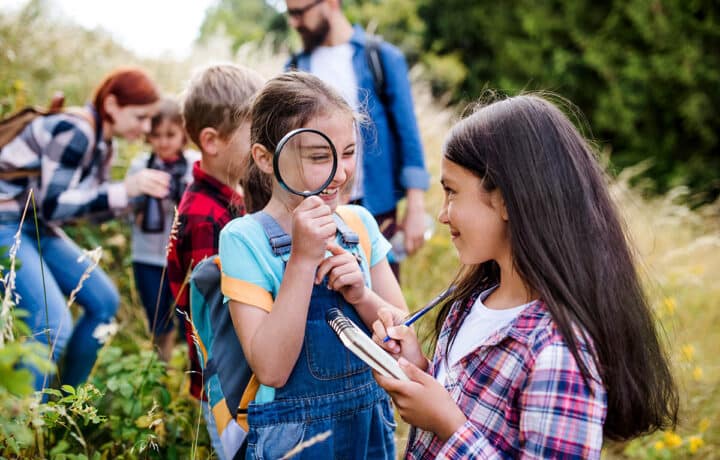 Group of school children with teacher on field trip in nature, learning science.